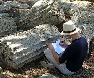Student der Historischen Bauforschung bei der zeichnerischen Dokumentation antiker Säulenfragmenten in Olympia