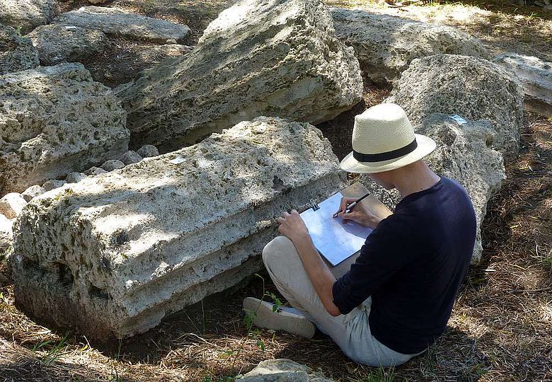 Student der Historischen Bauforschung bei der zeichnerischen Dokumentation antiker Säulenfragmenten in Olympia