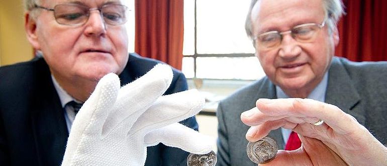 Stiftungsvorstand Professor Löwer (li.) und Stifter Dr. Trumpf begutachten die antiken Münzen. (Foto: Volker Lannert/Uni Bonn)