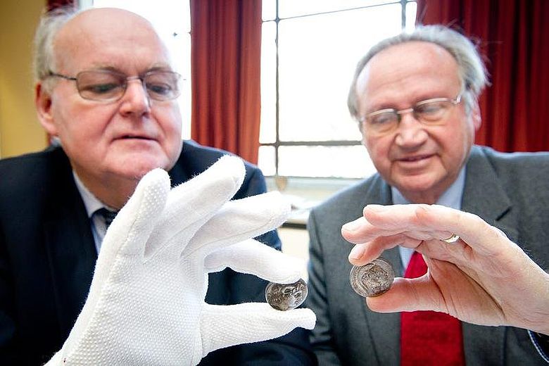 Stiftungsvorstand Professor Löwer (li.) und Stifter Dr. Trumpf begutachten die antiken Münzen. (Foto: Volker Lannert/Uni Bonn)