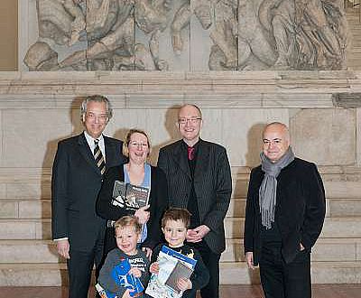 Michael Eissenhauer, Andreas Scholl und Yadegar Asisi (v. l.) begrüßen Familie Starck aus Berlin als 500.000 Besucher der Pergamon-Ausstellung (© Staatliche Museen zu Berlin, Foto: Achim Kleuker)