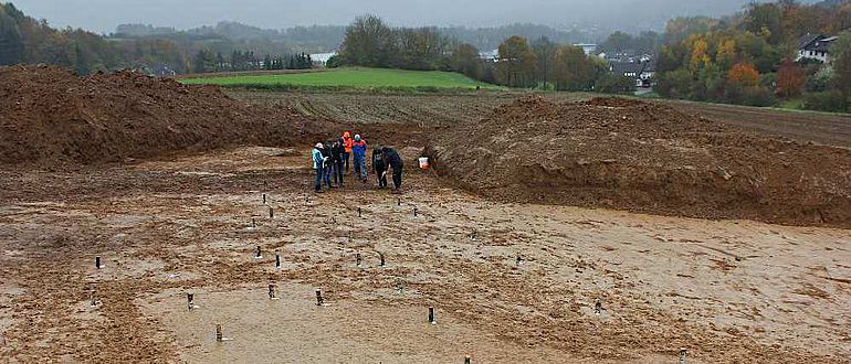 Um die Gebäudegrundrisse zu veranschaulichen, haben die Archäologen helle Birkenstammabschnitte auf die Pfostenspuren gestellt
