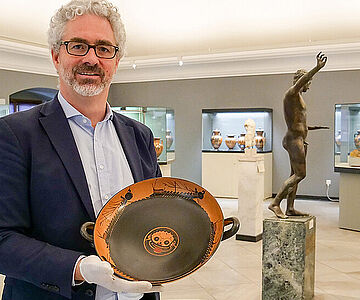 Jochen Griesbach-Scriba mit einer antiken Trinkschale im Martin von Wagner Museum der Universität Würzburg