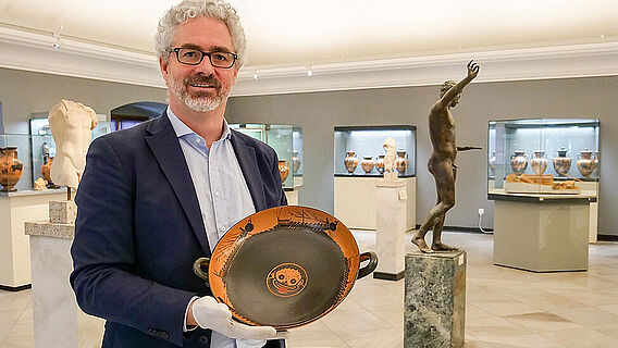 Jochen Griesbach-Scriba mit einer antiken Trinkschale im Martin von Wagner Museum der Universität Würzburg