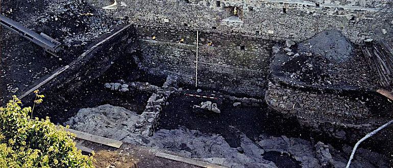 Blick von Norden auf die Grundmauern der spätantiken Eisenhütte, darüber die spätmittelalterliche Zinnenmauer