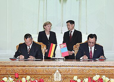 Prof. Dr. B. Enkhtuvshin und Dr. Michael Hanssler (links) bei der Unterzeichnung des Kooperationsabkommens. Im Hintergrund die Bundeskanzlerin Dr. Angela Merkel und der mongolische Premierminister Sukhbaatar Batbold (Foto: Gerda Henkel Stiftung)