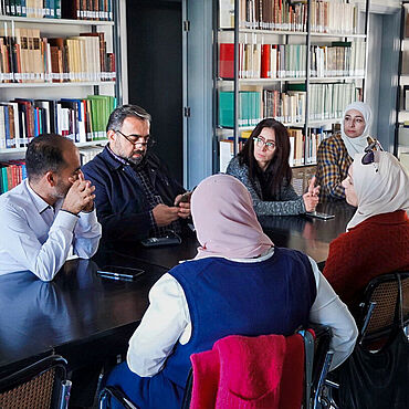 Stipendiatinnen und Stipendiaten aus Syrien diskutieren in Bibliothek
