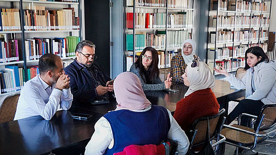 Stipendiatinnen und Stipendiaten aus Syrien diskutieren in Bibliothek