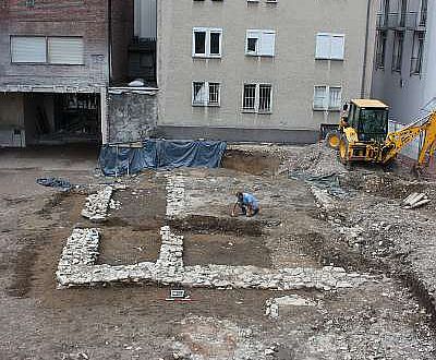 Eindrucksvoll sind die baulichen Spuren aus der Paderborner Marktsiedlung mit den Grundmauern des mächtigen Steingebäudes sowie einem Ofenfundament und einem Brunnen im Vordergrund. Im Hintergrund ist ein vollständig erhaltener feuerfester Speicher aus dem Mittelalter zu sehen. (Foto. LWL/Spiong)