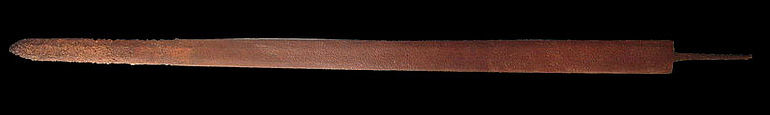 Abb. 2a: Eine spätrömische Reiterspatha aus dem 3./4. Jh. n. Chr.. Die Klinge ist 83 cm lang und 4 cm breit. Zur Klingenspitze hin sind tiefere Korrosionsgruben sichtbar, was auf eine gesonderte Härtung dieses am stärksten beanspruchten Bereichs einer Schwertklinge hinweist. Höher kohlenstoffhaltiger Stahl wird stärker von Korrosion in Mitleidenschaft gezogen als »weichere« Eisenwerkstoffe. Im vorderen Drittel sind mehrere Hiebscharten zu sehen. Klinge: Fundort unbekannt, Verbleib: Privatsammlung. (Foto: Jens Schneider, Gundelfingen) Abb. 2a: Eine spätrömische Reiterspatha aus dem 3./4. Jh. n. Chr.. Die Klinge ist 83 cm lang und 4 cm breit. Zur Klingenspitze hin sind tiefere Korrosionsgruben sichtbar, was auf eine gesonderte Härtung dieses am stärksten beanspruchten Bereichs einer Schwertklinge hinweist. Höher kohlenstoffhaltiger Stahl wird stärker von Korrosion in Mitleidenschaft gezogen als »weichere« Eisenwerkstoffe. Im vorderen Drittel sind mehrere Hiebscharten zu sehen. Klinge: Fundort unbekannt, Verbleib: Privatsammlung. (Foto: Jens Schneider, Gundelfingen)