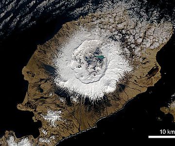 Auf der Insel erhebt sich Okmok als breiter Schildvulkan 1073 Meter über dem Meeresspiegel