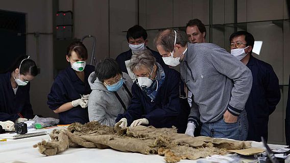 Deutsche und chinesische Wissenschaftler untersuchen einen Fellmantel aus Hami, Xinjiang (Foto: DAI)