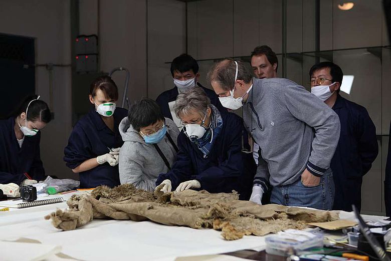 Deutsche und chinesische Wissenschaftler untersuchen einen Fellmantel aus Hami, Xinjiang (Foto: DAI)