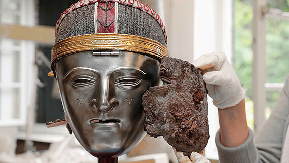 Maskenfragment neben Nachbildung einer Gesichtsmaske der Bataver