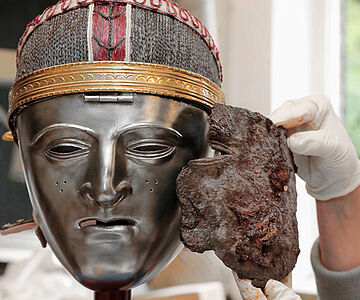 Maskenfragment neben Nachbildung einer Gesichtsmaske der Bataver