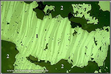 Polierter Erzanschliff mit lamellarem Antimonit (1) und Quarz (2) Polierter Erzanschliff mit lamellarem Antimonit (1) und Quarz (2)