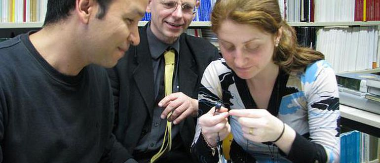 Mohammed Younis (v. l.) aus Ägypten, Stefan Heidemann aus Jena und Huda Subeh aus Syrien betrachten alte Münzen im Orientalischen Münzkabinett der Universität Jena (Foto: Friederike Enke/FSU)