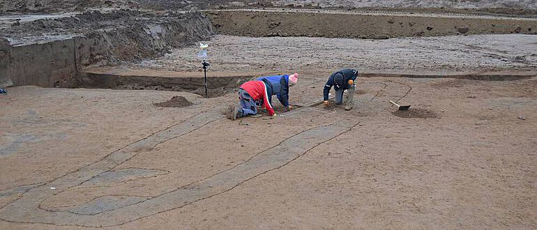 Der Graben als Hügeleinfassung des bronzezeitlichen Grabes stellt sich als dunkele Verfärbung dar