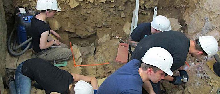 Vor dem großen Westprofil dringen die Studierenden auf dem Vorplatz der Blätterhöhle sicher und präzise in immer tiefere Schichten vor